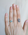 Hand with a ring and a small tattoo on a plain background