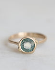 Gold ring with a blue gemstone on a light gray background