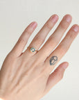Hand wearing a ring with a blue gemstone on a plain background