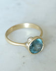 teal montana sapphire set within a bezel of a yellow gold ring, with white gold barnacles and diamonds