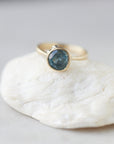 teal montana sapphire set within a bezel of a yellow gold ring, with white gold barnacles and diamonds