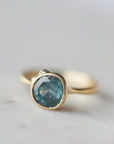teal montana sapphire set within a bezel of a yellow gold ring, with white gold barnacles and diamonds