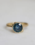 Gold ring with a blue gemstone on a light gray background