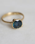 Gold ring with a blue gemstone on a light gray background