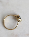 Gold ring with a blue stone on a light marble background