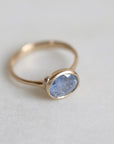 Gold ring with a blue gemstone on a light gray background