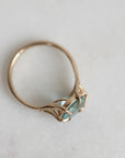 Gold ring with a green gemstone on a light gray background