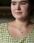 Woman wearing a green and white checkered dress with a necklace.