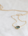 Necklace with a teal gemstone pendant on a white fabric background
