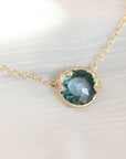 Necklace with a teal gemstone pendant on a white fabric background