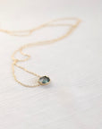 Necklace with a teal gemstone pendant on a white fabric background