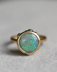 Gold ring with a green opal stone on a gray background