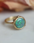 Gold ring with a green opal on a light background