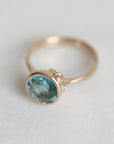 Gold ring with a blue gemstone on a light gray background