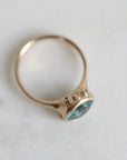 Gold ring with a blue gemstone on a light background