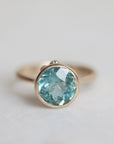 Gold ring with a blue gemstone on a light gray background