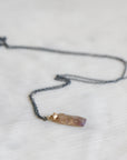 Necklace with an amber colored opal pendant on a light gray background