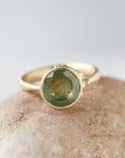 mossy green montana sapphire set in a gold ring with barnacles