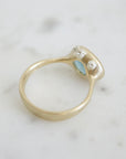 An oblong faceted aquamarine is set in a gold band with little silver barnacles around the setting. Back view.