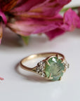 a green egg montana sapphire is in a ring of gold branches and white gold roses. photographed with decaying roses.