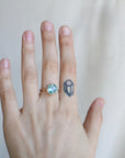 Hand wearing a ring with a gemstone on a plain background