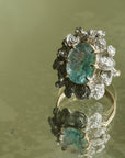 A ring with a wreath of silver roses around a pale blue tourmaline stone
