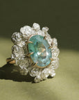 A ring with a wreath of silver roses around a pale blue tourmaline stone