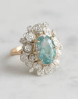A ring with a wreath of silver roses around a pale blue tourmaline stone