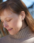 Earring studs: carved moonstone beetles with gold prongs, photographed on person.