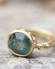 natural light on pale teal montana sapphire set in yellow gold ring with barnacles