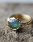 natural light on pale teal montana sapphire set in yellow gold ring with barnacles