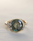 Gold ring with a green gemstone and barnacles on a light background