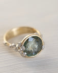 Gold ring with a green gemstone and barnacles on a light background