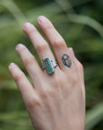 long, rectangular tourmaline stone set with prongs next to a diamond baguette. The ring is platinum, and shown on hand.