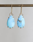 Pair of blue teardrop earrings on a gray background