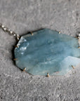 Necklace with a large, faceted blue stone pendant on a gray surface