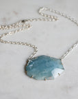 Necklace with a blue pendant on a marble surface