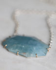 Necklace with a blue stone pendant on a light gray background