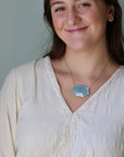 Woman wearing a white blouse and necklace with a gray background