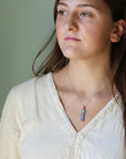 Woman wearing a necklace with a pendant against a neutral background