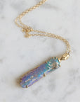 Necklace with a colorful opal and gold face with crescent moon on a marble surface