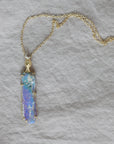 Necklace with a colorful opal and gold face with crescent moon on a textured fabric surface
