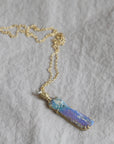 Necklace with a colorful opal and gold face with crescent moon on a textured fabric surface