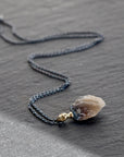 Necklace with a clambshell fossil pendant on a stone background
