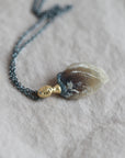 Necklace with a clambshell fossil pendant on a textured fabric background