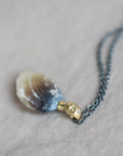 Necklace with a clambshell fossil pendant on a textured fabric background