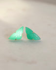 Pair of green butterfly-shaped earrings on a light gray background