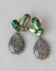 Pair of earrings with green and gray stones on a light background