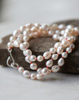 necklace made of multi sized white freshwater baroque pearls strung on coral silk with silver barnacles and fish hook clasp