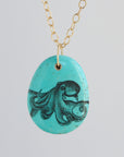 Turquoise pendant with octopus design on a gold chain against a light gray background